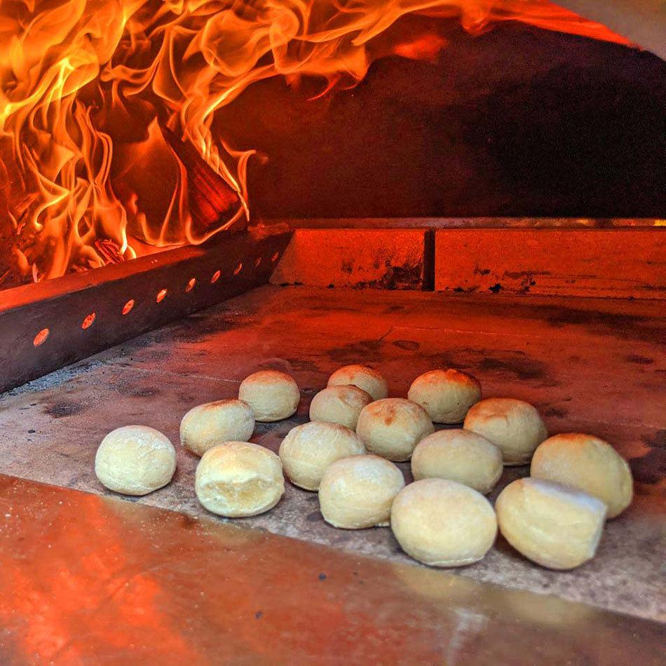 Clementi Wood Fired Pizza Oven 100x80 close up showing doughballs cooking with flames. The Outdoor Grill Company.