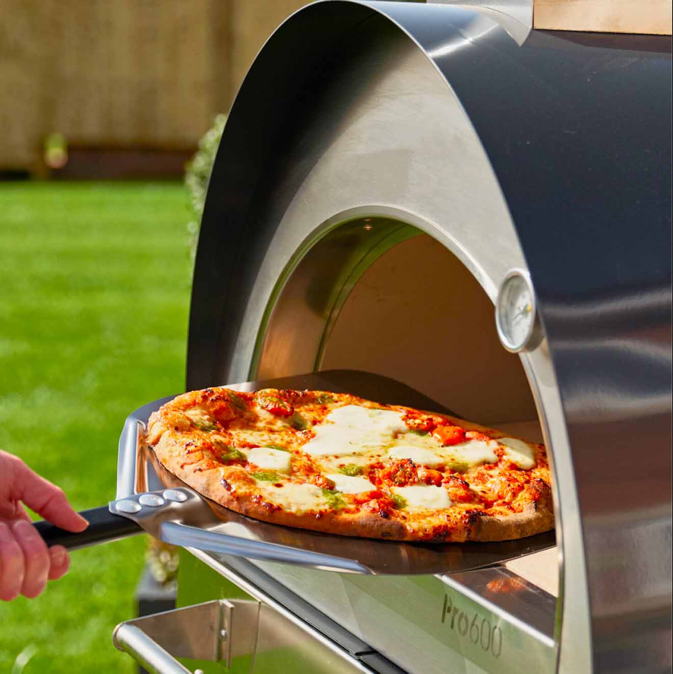 Igneus - Pro 600 Wood Fired Pizza Oven - shows a pizza being put in the oven for cooking