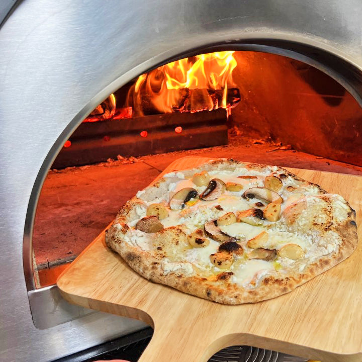 Igneus - Pro 600 Wood Fired Pizza Oven - Pizza on a wooden board being put into the oven