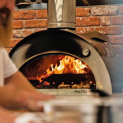 Igneus - Pro 750 Wood Fired Pizza Oven - Shown in front of a brick wall all fired up